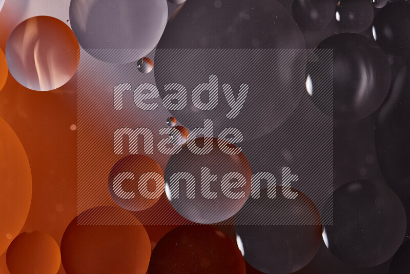 Close-ups of abstract oil bubbles on water surface in shades of black and orange