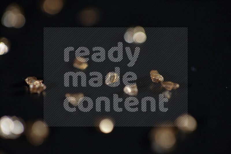 Gold shimmering fragments of glass scattered on a black background