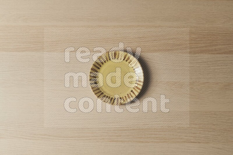 A multicolored pottery plate on light wooden background