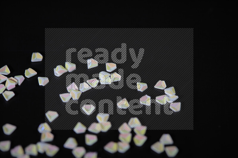 قطع صغيرة بلاستيكية ملونة للزينة متناثرة على خلفية سوداء