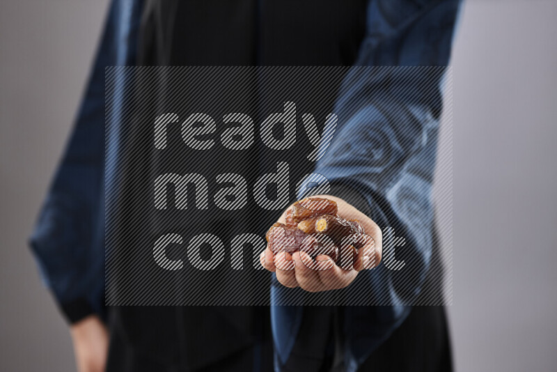 امرأة ترتدي عباءة تحمل أنواع مختلفة من التمر في أوضاع متعددة