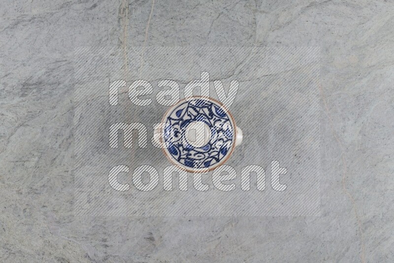 A multicolored pottery pot with its lid on grey marble background