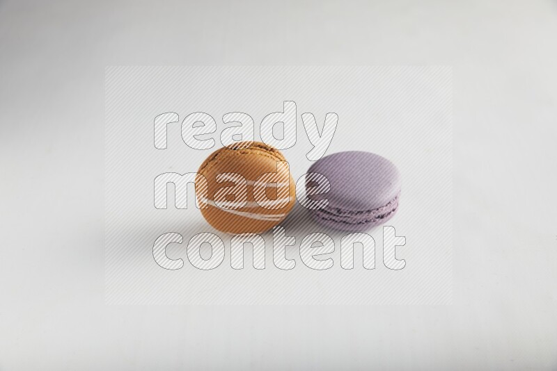 45º Shot of of two assorted Brown Irish Cream, and Purple Blueberry macarons on white background