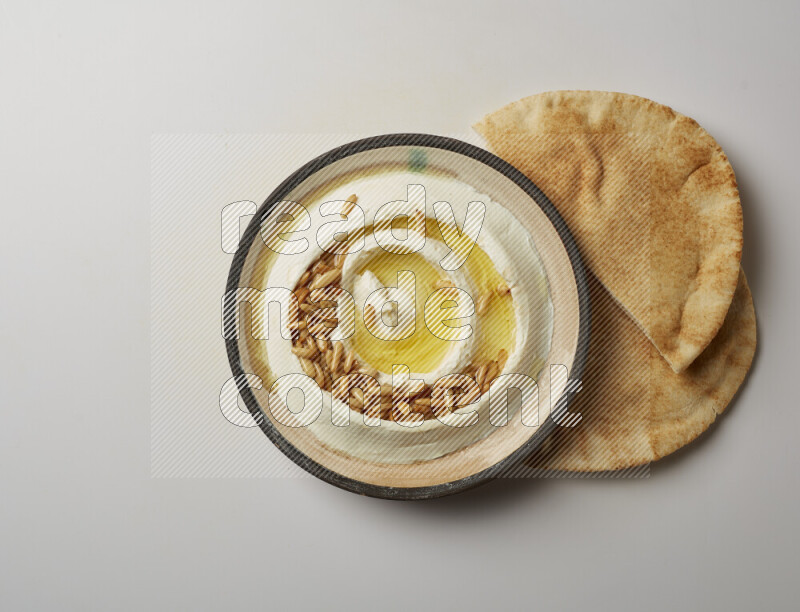 Lebnah garnished with pine nuts in a pottery plate on a white background