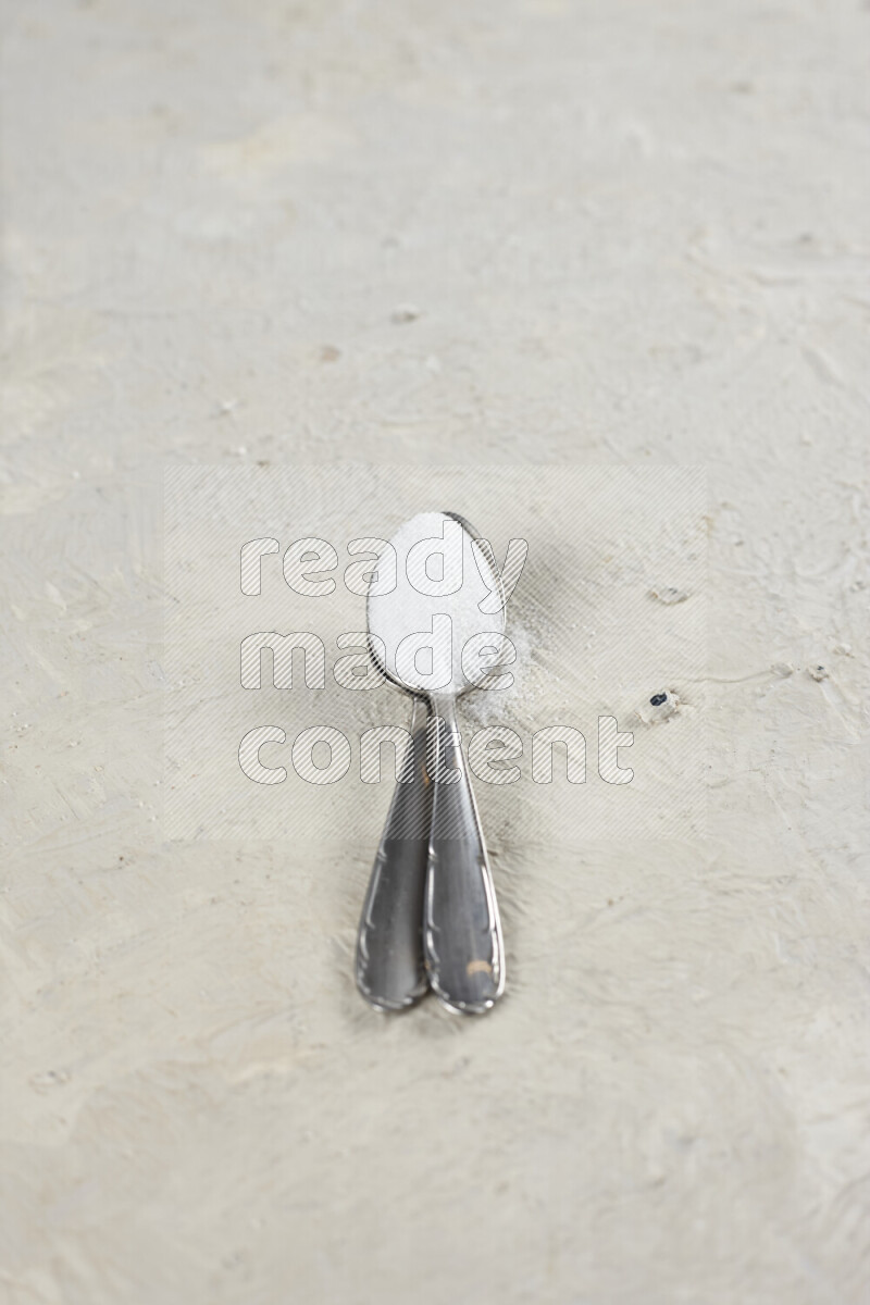 ملعقتان معدنيتان ممتلئتان بملح الطعام الناعم وملح الهايمالايا الناعم على خلفية بيضاء