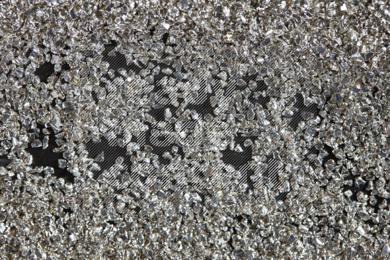 Silver shimmering fragments of glass scattered on a black background