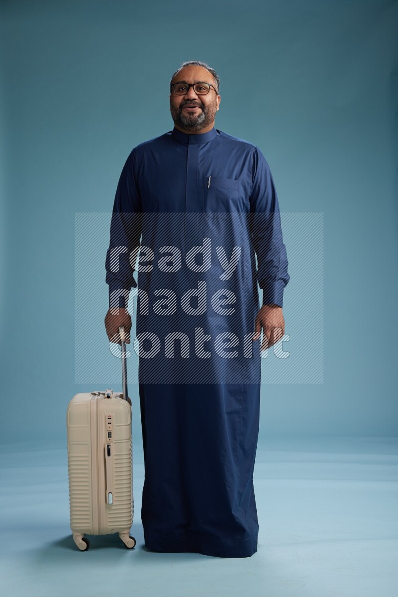 Saudi Man without shimag Standing pulling travel bag on blue background