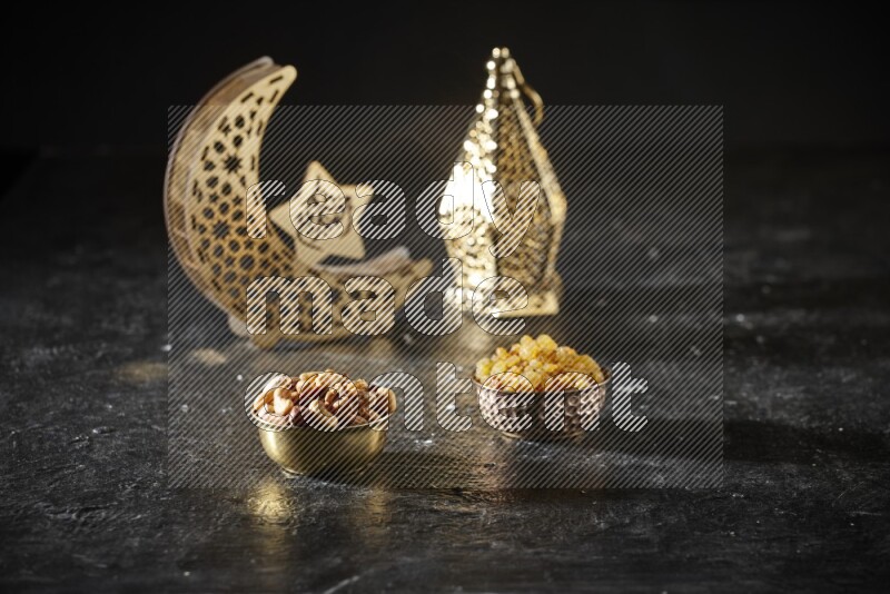 مكسرات في وعاء معدني مع الزبيب بجانب فوانيس ذهبية علي خلفية سوداء