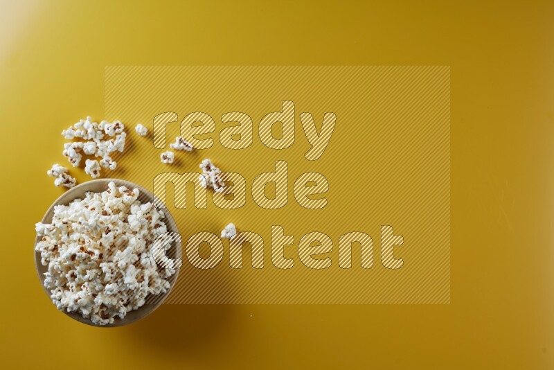 A multicolored ceramic plate full of popcorn with popcorn beside it on a yellow background in different angles