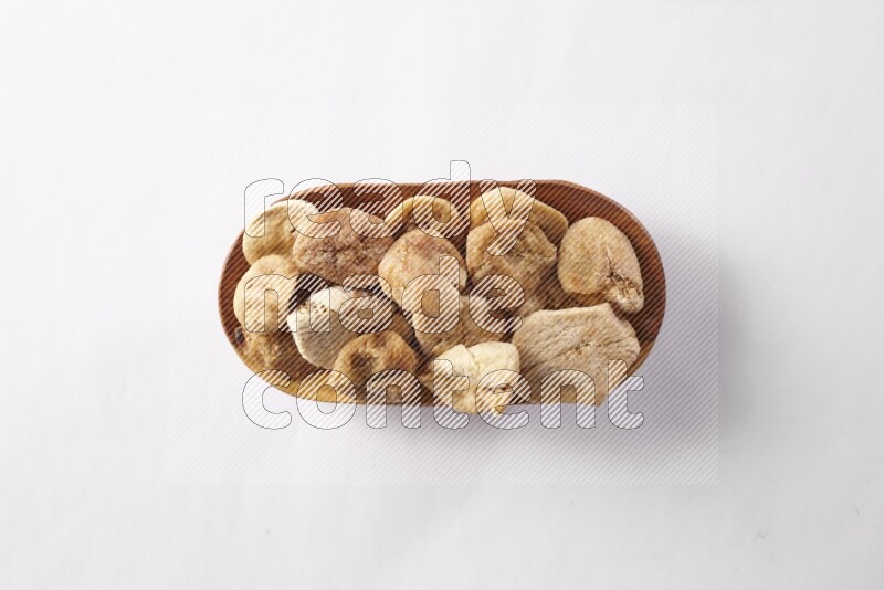 Dried figs in a wooden plate on white background