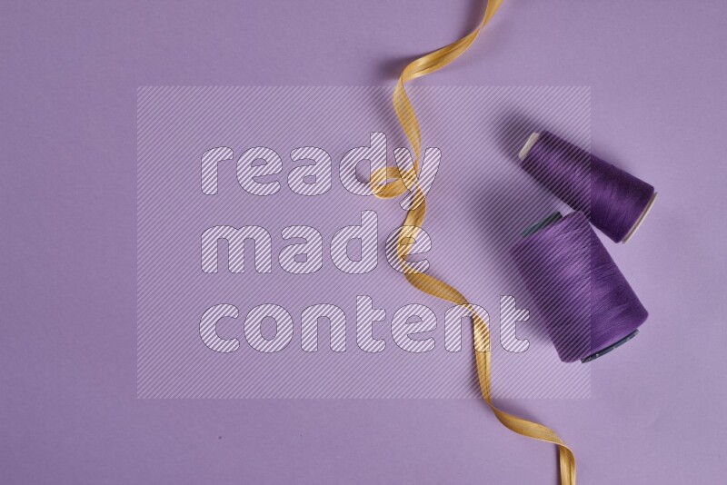 A yellow and purple collection of sewing and tailoring tools arranged on a purple background