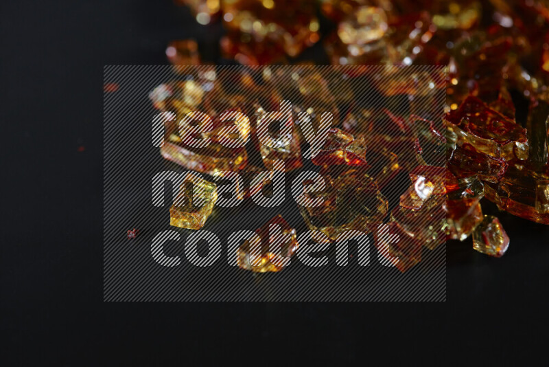 Transparent orange fragments of glass scattered on a black background