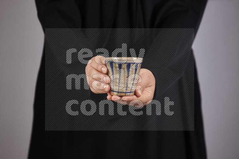 A woman in black abaya holding different pottery essentials in different positions