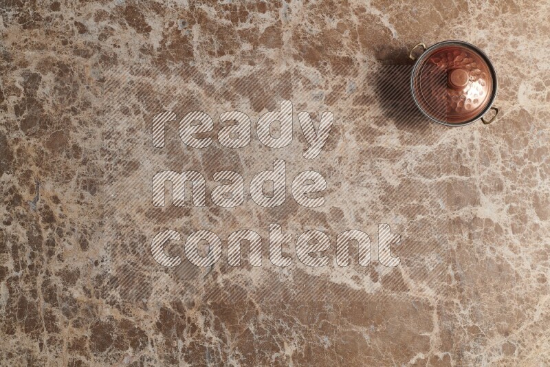 A small copper pot on beige marble background