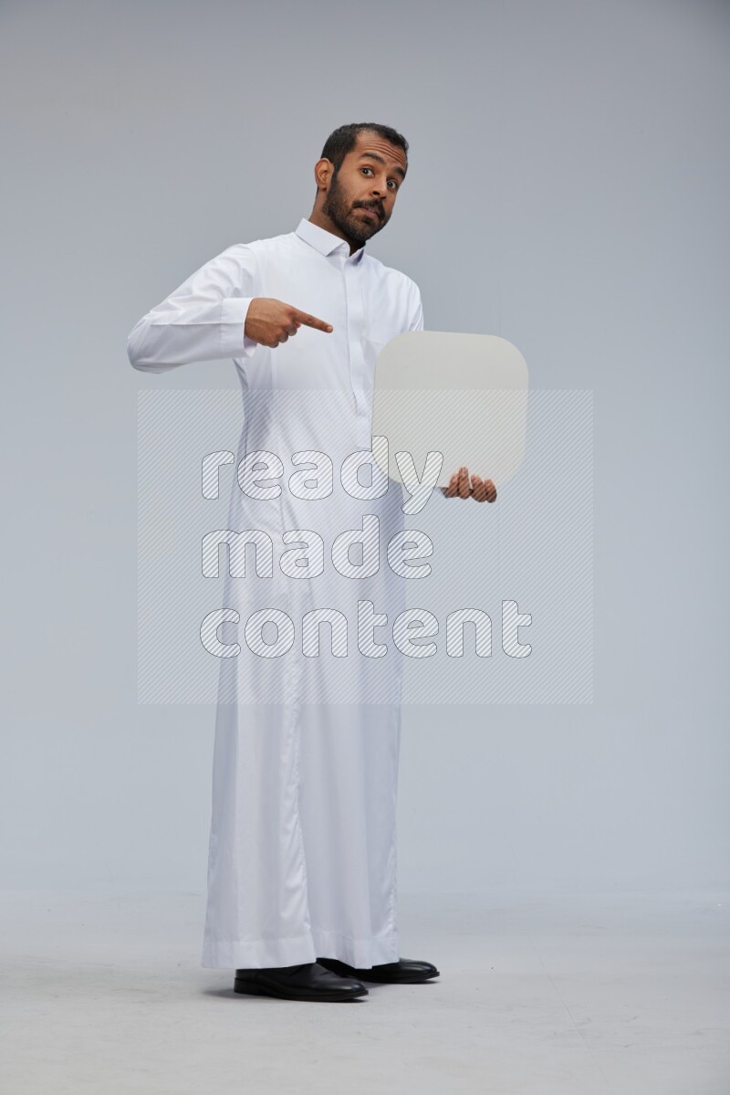 Saudi man wearing Thob standing holding social media sign on Gray background