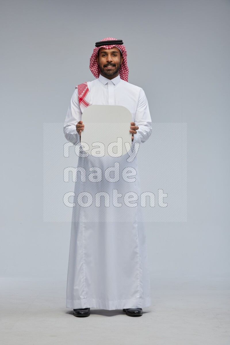 Saudi man Wearing Thob and shomag standing holding social media sign on Gray background