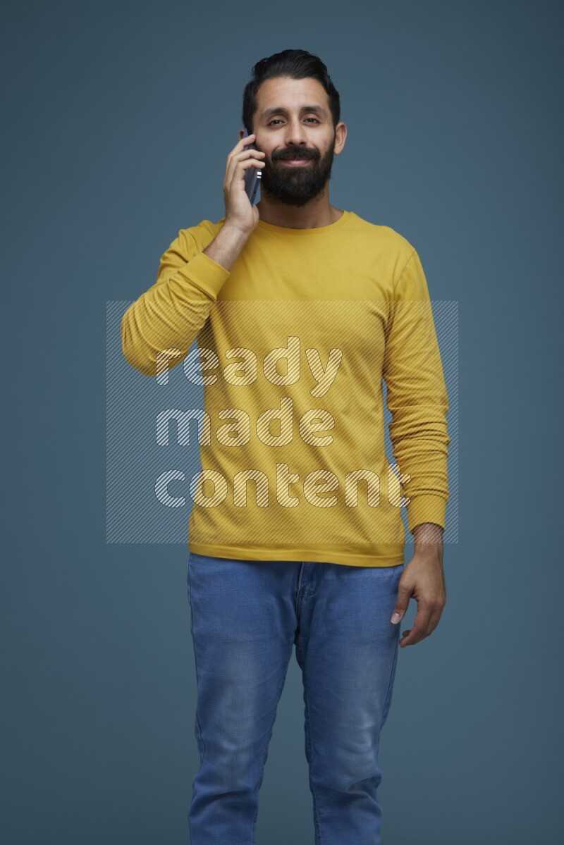 A man having a calling in a blue background wearing a yellow shirt