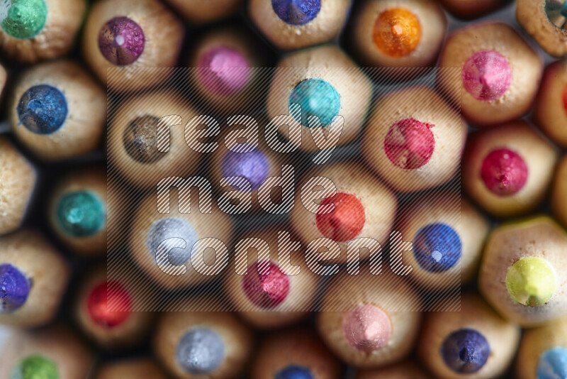 The image captures top view shot of sharpened colored pencils on grey background