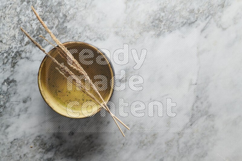 Wheat stalks on multicolored pottery oven plate on grey marble background