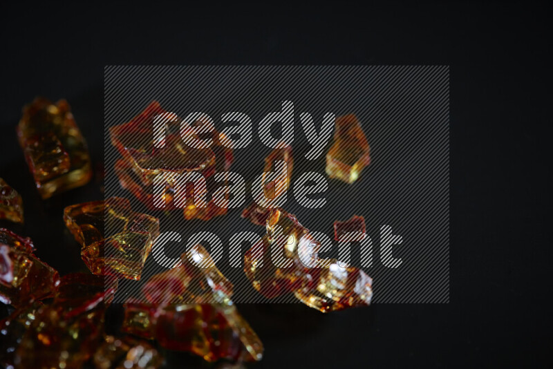 Transparent orange fragments of glass scattered on a black background