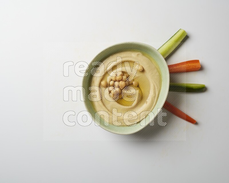 Hummus in a green plate garnished with roasted chickpeas  on a white background