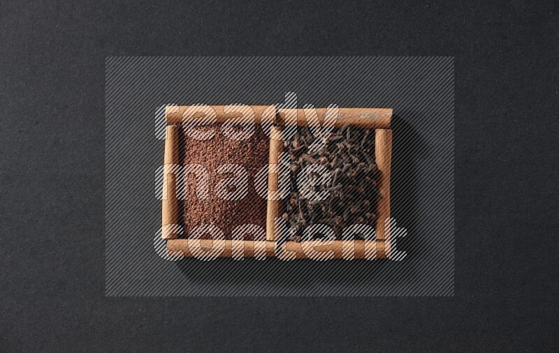 2 squares of cinnamon sticks full of garden cress and cloves on black flooring