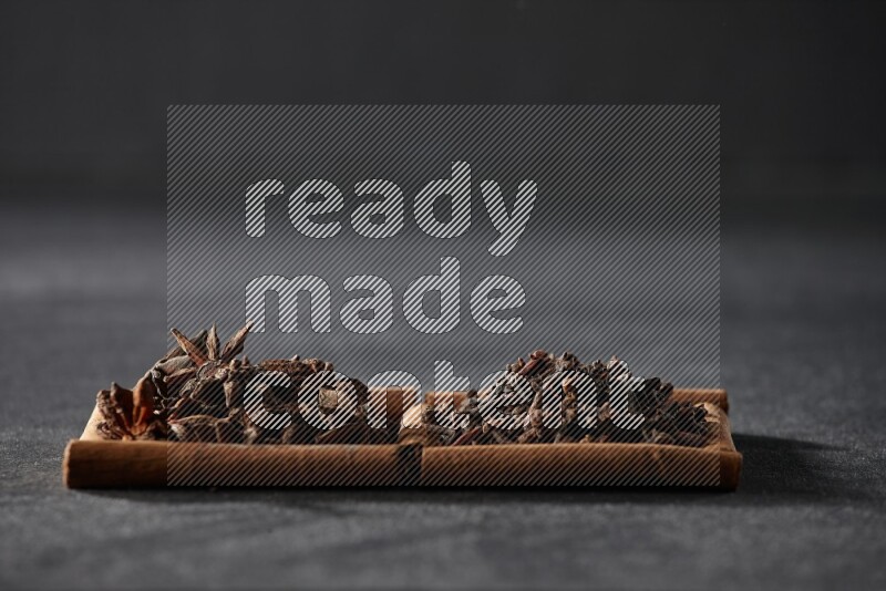 2 squares of cinnamon sticks full of star anise and cloves on black flooring
