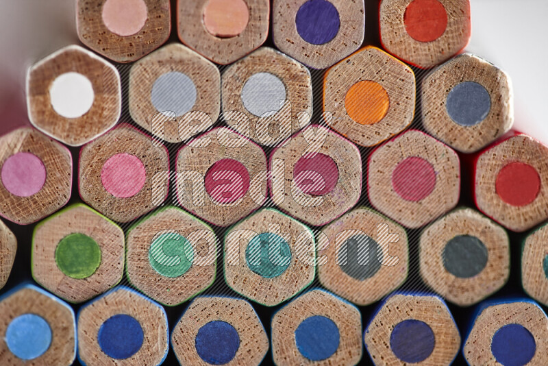 A close-up of the tips of colored pencils arranged in a bundle on white background