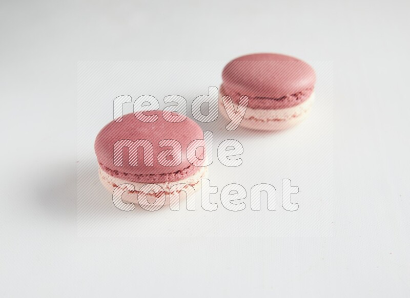 45º Shot of two Pink Litchi Raspberry macarons on white background