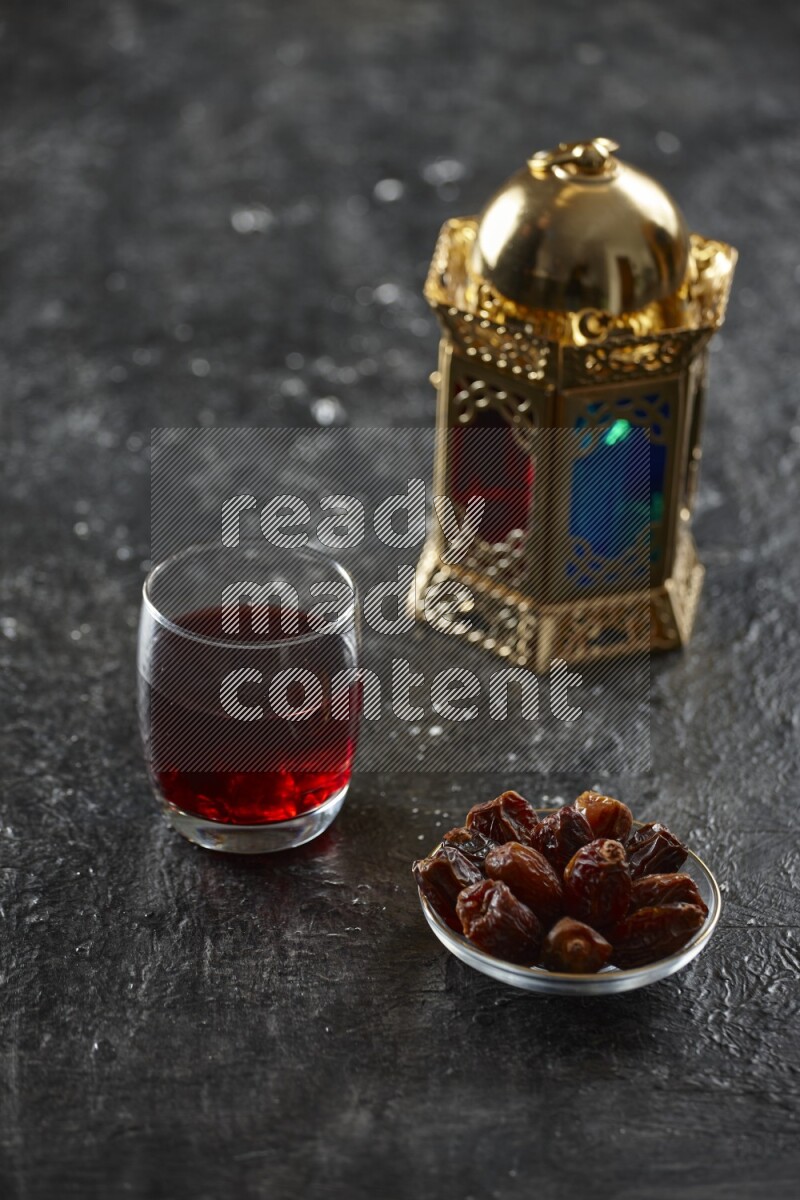 A golden lantern with different drinks, dates, nuts, prayer beads and quran on textured black background