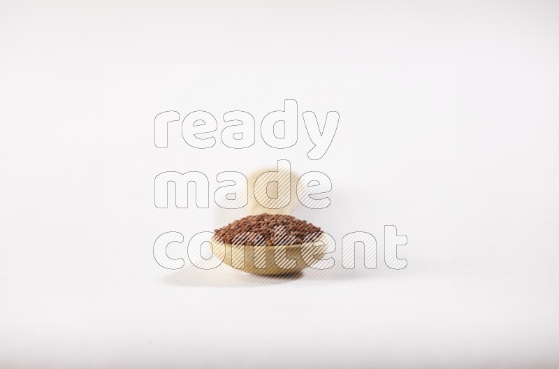 A wooden spoon full of garden cress seeds on a white flooring
