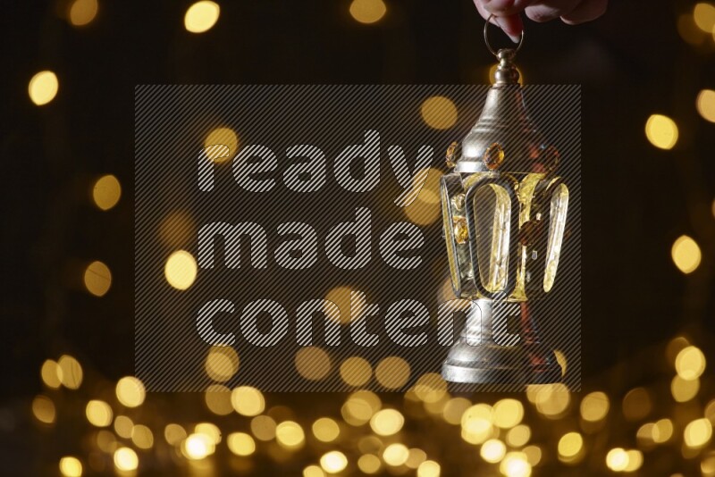 A traditional ramadan lantern surrounded by glowing fairy lights in a dark setup