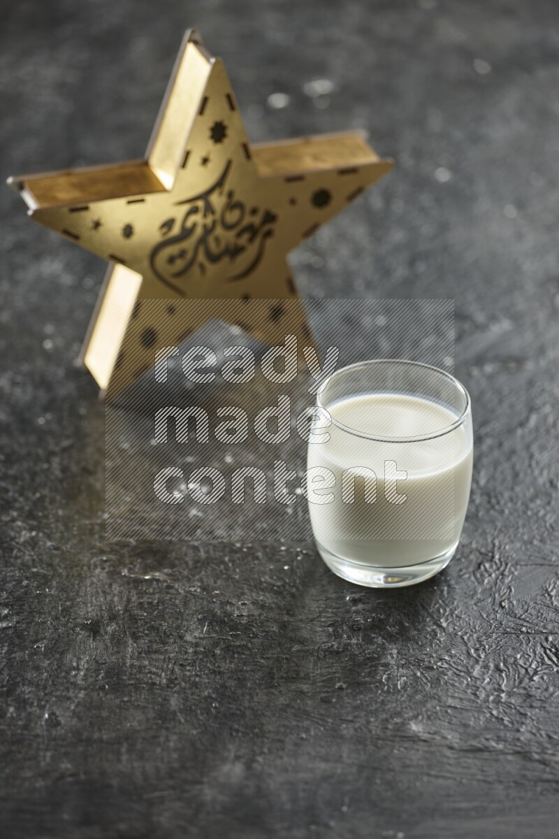 فانوس خشبي نجمي باللون الذهبي مع مشروبات مختلفة وتمر ومكسرات وسبحة صلاة وقرآن على خلفية سوداء