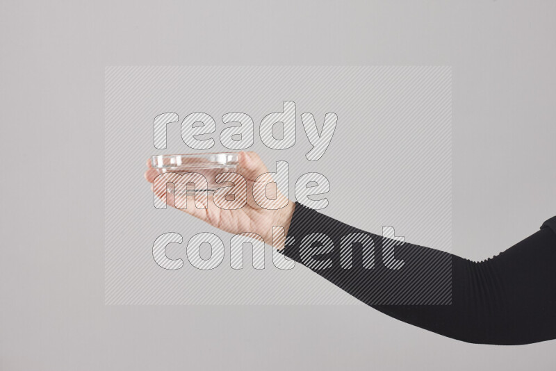 A woman in black abaya holding different glassware in different positions