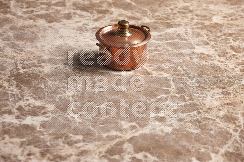 A small copper pot on beige marble background