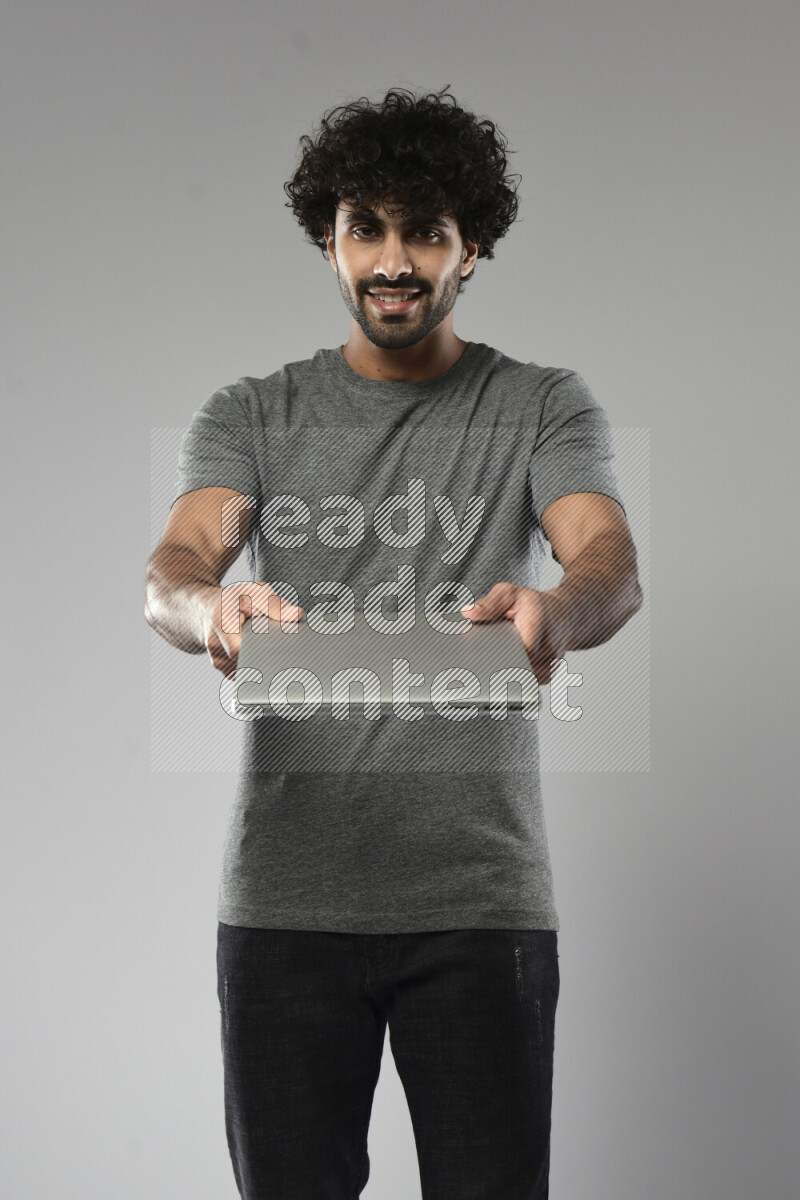 رجل يرتدي ملابس كاجوال يحمل لاب توب علي خلفية بيضاء