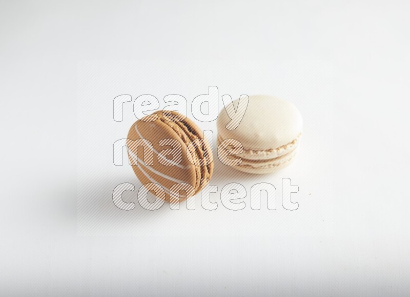 45º Shot of of two assorted Brown Irish Cream, and White Caramel fleur de sel macarons on white background