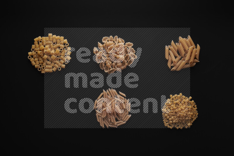 Different pasta types in bunches on black background