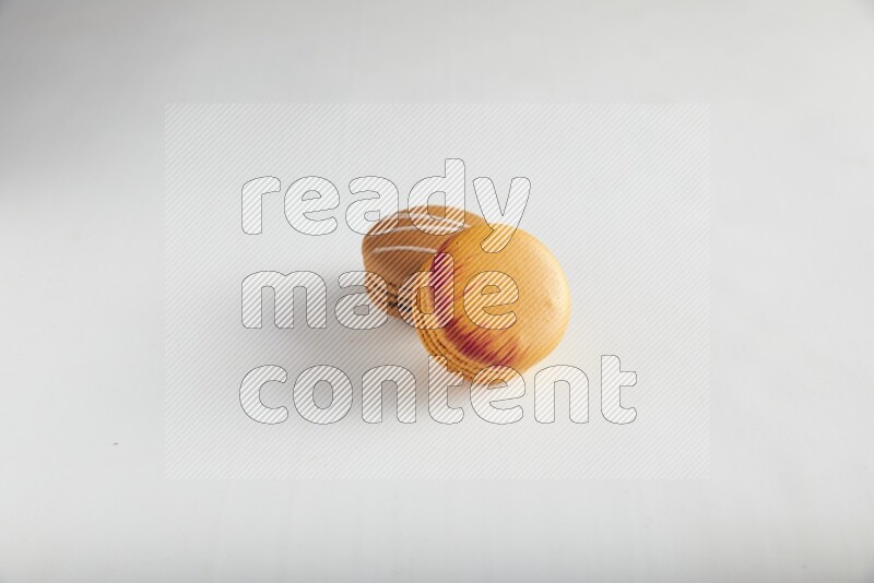 45º Shot of of two assorted Brown Irish Cream, and Orange Exotic macarons on white background