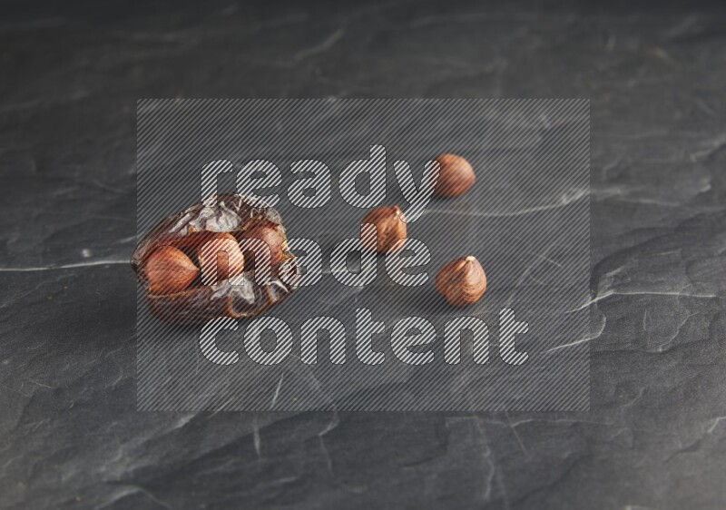 hazelnuts stuffed madjoul date on a black textured background