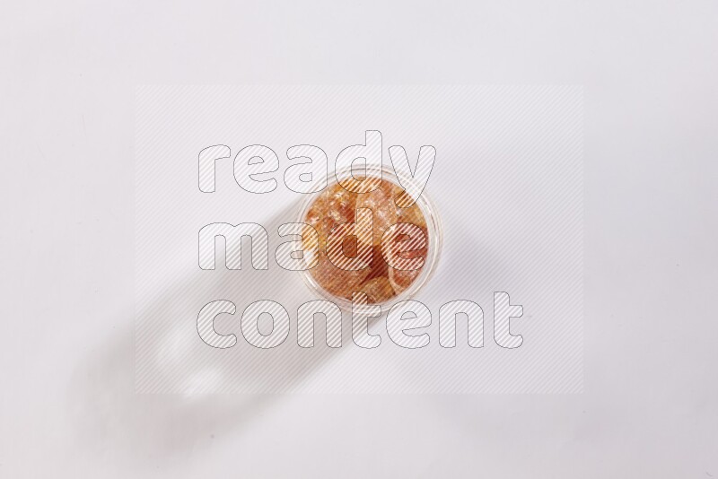 A glass jar filled with gum arabic on white flooring