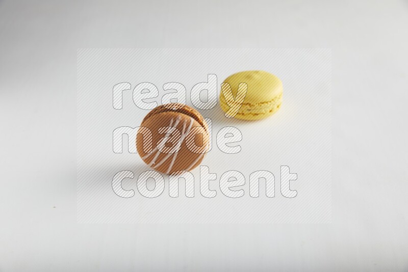 45º Shot of of two assorted Brown Irish Cream, and Yellow Lemon macarons on white background