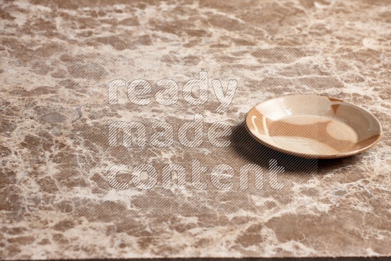 A multicolored pottery plate on beige marble background
