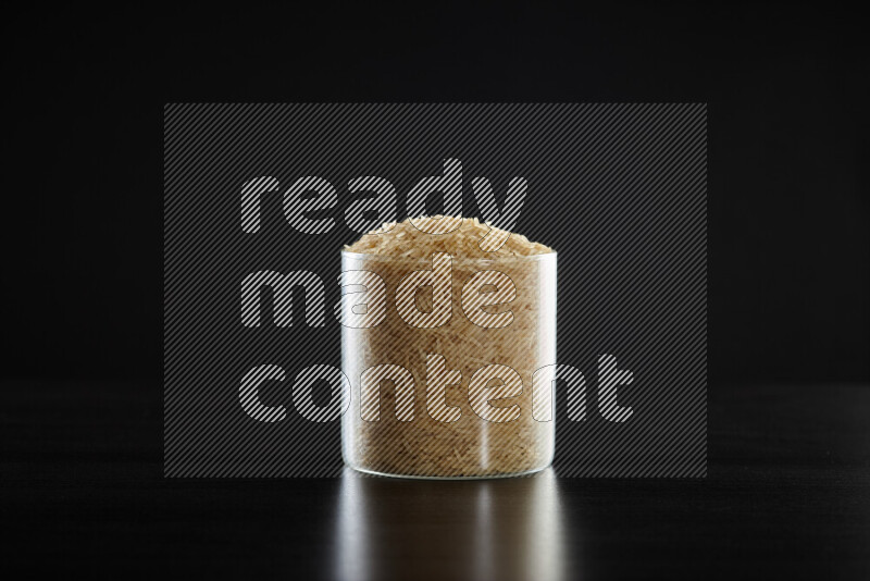 Basmati golden rice in a glass jar on black background