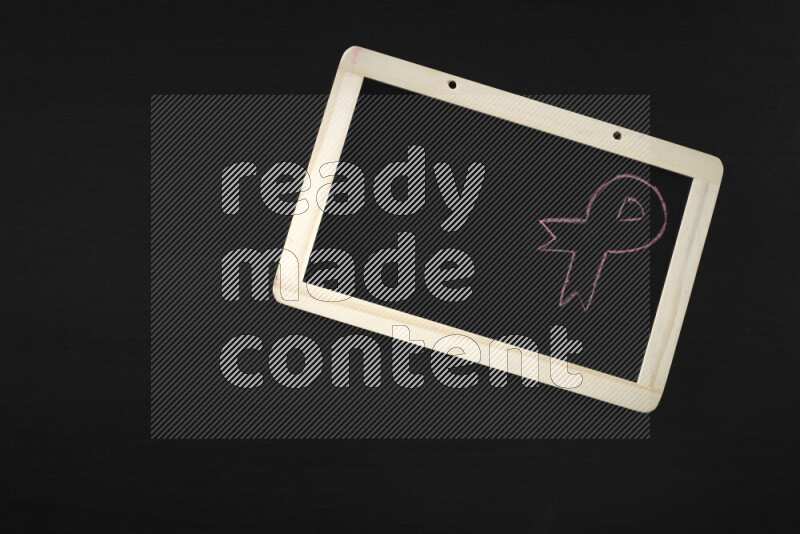 A drawing of pink ribbon on blackboard on black background