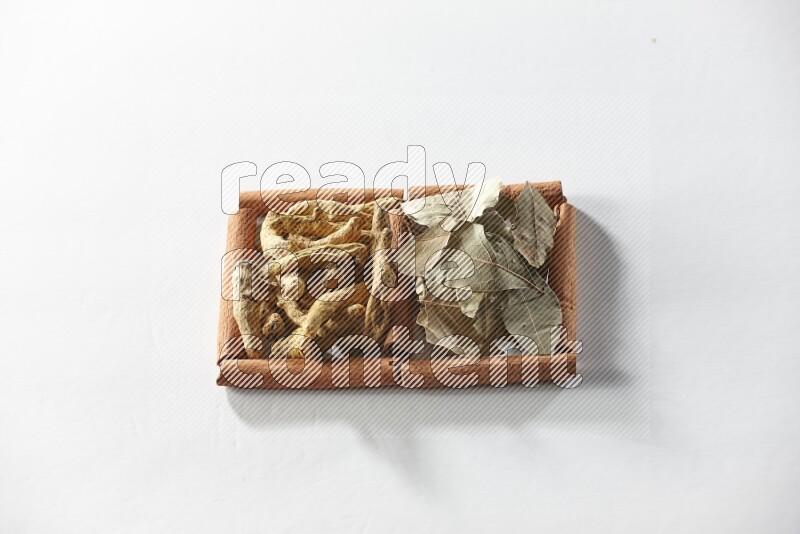 مربعان من أعواد القرفة ممتلئان بأصابع الكركم وأوراق الغار علي خلفية بيضاء