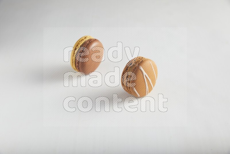 45º Shot of of two assorted Brown Irish Cream, and Yellow, and Brown Chai Latte macarons on white background