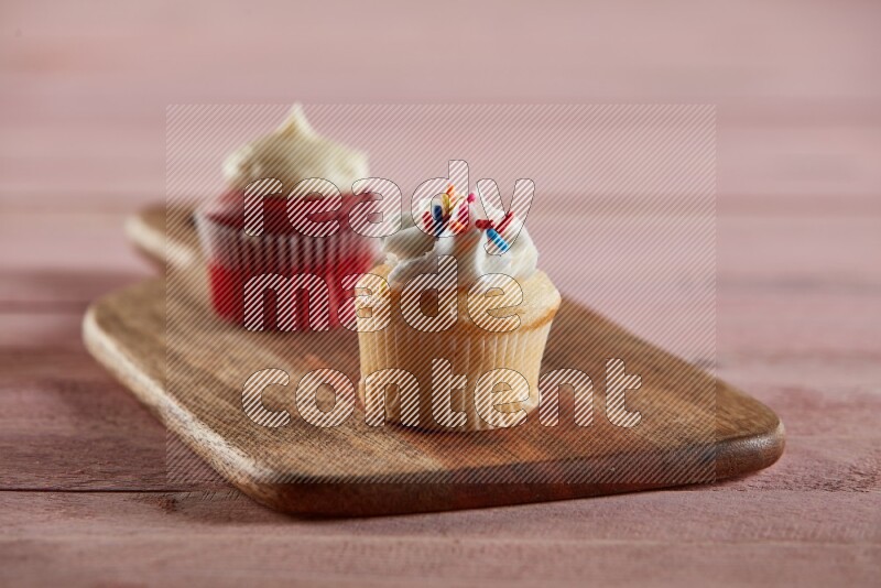 Vanilla mini cupcake topped with cream on a wooden board