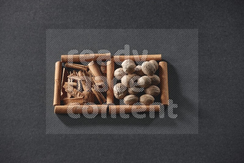 مربعان من أعواد القرفة ممتلئان بقطع من القرفة وجوزة الطيب علي خلفية سوداء