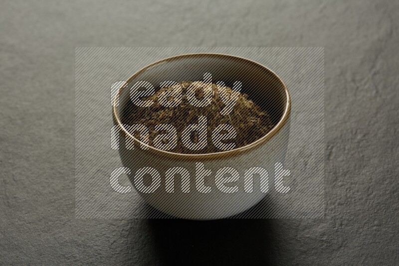 multi color round sauce bowl filled with herbs on grey textured countertop